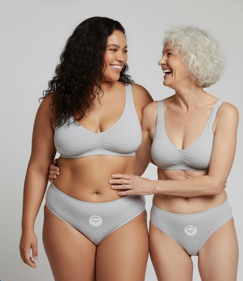Two women wearing gray underwear with a visible brand logo on a plain background